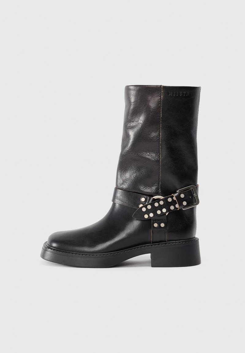 Bottines en cuir noir avec bout rond, talon épais et une sangle décorative ornée de boucles et de clous argentés. Texture lisse.