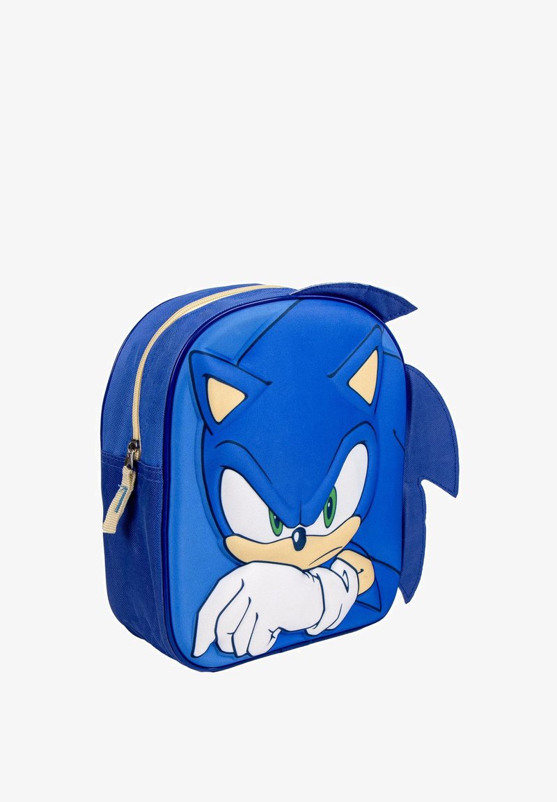 Sac à dos bleu avec un design de personnage imprimé, arbore des yeux verts et des gants blancs. Tissu doux avec une fermeture à glissière et des fausses pointes.