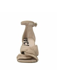 Beige suède hakken sandaal met een geknoopt voorkantontwerp, enkelbandje, open teen en een platte, brede hak. Glad oppervlak en moderne vorm.