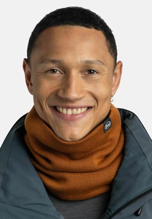 Brown knitted neck warmer with a soft texture, featuring a black circular logo tag. The background is plain white.