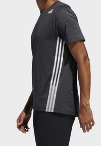 Černé sportovní tričko s krátkými rukávy, třemi svislými bílými pruhy po straně a kulatým výstřihem. Vyrobeno z lehkého materiálu.