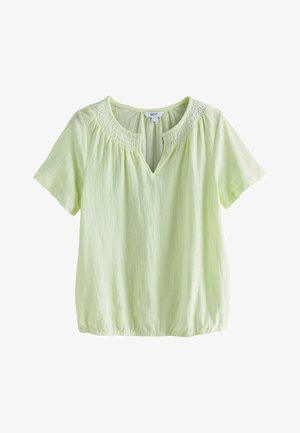 Lysegrøn bluse med korte ærmer, med smocket rund halsudskæring, V-formet frontslids og indsamlet elastisk kant, hængende mod hvid baggrund.
