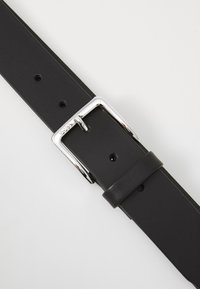 Curea din piele neagră cu un design elegant, cataramă metalică argintie, cinci găuri ajustabile și o textură netedă pe toată lungimea.