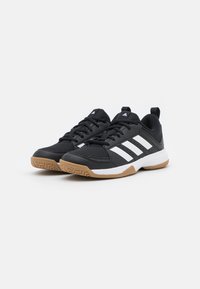 Scarpe sportive nere con una tomaia testurizzata, strisce bianche di accento e una suola in gomma naturale con un motivo a zigzag. Chiusura con lacci e linguetta sul tallone.