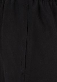 Tessuto nero con una superficie liscia, dotato di una cucitura verticale centrale e una vita elastica per una vestibilità regolabile. Design semplice con dettagli minimi.
