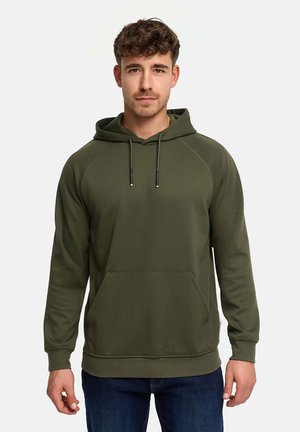 Ung mand iført olivengrøn hættetrøje med frontlomme, stående mod en ensfarvet lys baggrund, vendt fremad.