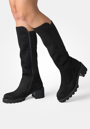 Botas negras de ante hasta la rodilla, con cremallera lateral, suela de plataforma gruesa y suela de goma texturizada para agarre.