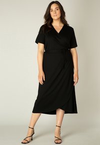 Zwarte wikkeljurk met korte mouwen en een strikceintuur, met een v-halsontwerp en een asymmetrische zoom tot op de knie. Glad stof textuur.