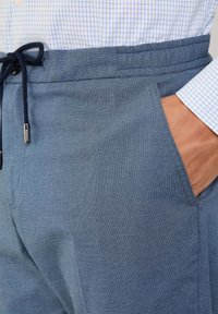 Pantaloni jogger blu testurizzati con vita elastica e coulisse, dotati di tasche laterali e un delicato motivo intrecciato.