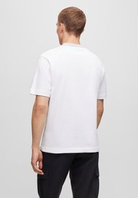 White cotton t-shirt with a crew neck, short sleeves, and a plain design, viewed from the back. No visible logos or patterns.