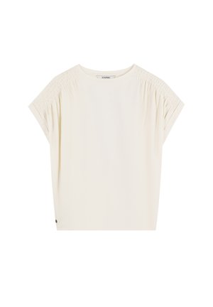 Top de manga corta color crema con detalles fruncidos en las costuras de los hombros, escote redondo y un corte relajado. Tela suave y ligera.