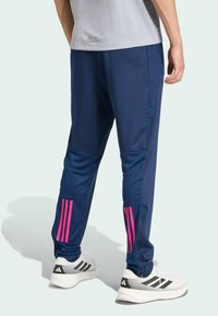 Navy athletic pants with pink stripes on the lower legs, featuring a tapered fit and zippered pockets, made from lightweight material.