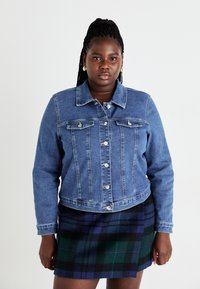 Τζάκετ τζιν σε ανοιχτό μπλε χρώμα με γιακά, μπροστινές τσέπες και ασημί κουμπιά. Συνδυασμένο με μίνι φούστα σε μαύρο και πράσινο καρό.