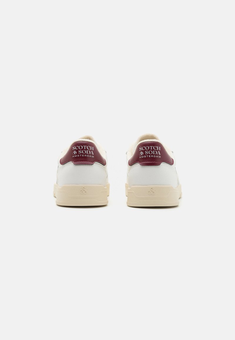 Witte sneakers met crèmekleurige zolen, voorzien van burgundy leren hielaccenten en branding op de achterkant. Glad textuur, atletisch ontwerp.