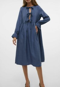 Modra, krilna obleka iz lahkega materiala s dolgimi rokavi, okroglo dekoltejem in zavezanjem spredaj. Oblika razširjenega krila.