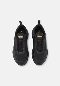 Czarne buty sportowe z siateczkową i skórzaną cholewką, wyposażone w sznurowadła, pętelkę do zakładania oraz złote logo "PUMA" na języku. Zaokrąglony kształt noska.