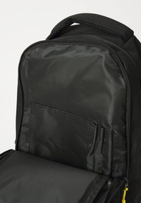Black backpack with a smooth, nylon exterior. Features a zippered opening, inner pocket with multiple slots, and a sturdy fabric handle.