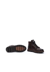 Brown leather boots with a glossy finish, featuring metal eyelets, laces, a textured black rubber sole, and a side zipper for easy wearing.