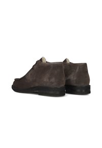 Chaussures de cheville en daim marron avec un bout arrondi, un laçage et un petit talon en caoutchouc noir. Texture lisse avec des variations de nuances subtiles.
