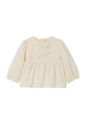 Cream-colored long-sleeve baby blouse with textured fabric, two decorative bows on the chest, and gathered waist detail.