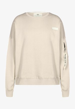 Beiger Pullover mit Rundhalsausschnitt, gerippten Bündchen und Saum. Hat ein Patch auf der Brust und eine Reißverschlusstasche am Ärmel mit einem Etikett.