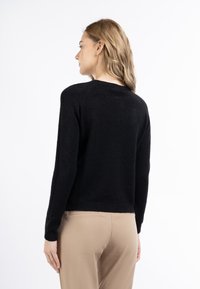 Maglione nero lavorato a maglia con scollo rotondo, maniche lunghe e dettagli texture. Finitura liscia, design cropped e orlo a costine.