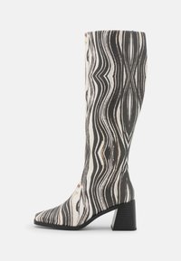 Botas até ao joelho com um padrão de ondas em preto e branco. Feitas de material sintético, com biqueira quadrada e salto bloco.