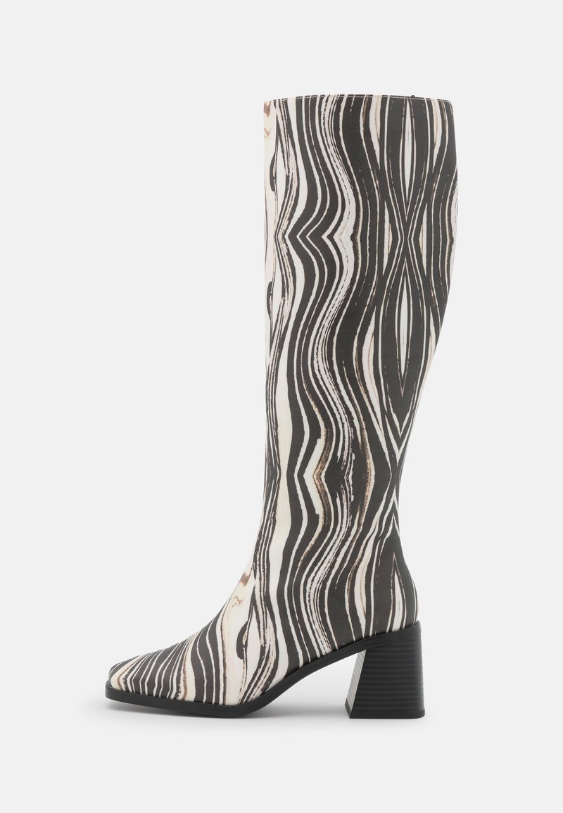 Botas até ao joelho com um padrão de ondas em preto e branco. Feitas de material sintético, com biqueira quadrada e salto bloco.