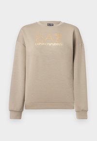 Μπεζ φούτερ με μακριά μανίκια, που διαθέτει χρυσή γκλίτερ επιγραφή "EA7" και χρυσό λογότυπο "EMPORIO ARMANI" στο μπροστινό μέρος.