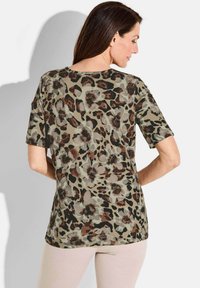 T-shirt à manches courtes en tissu doux, avec un imprimé floral-leopard dans des tons naturels de beige, marron et noir ; encolure ronde et coupe décontractée.