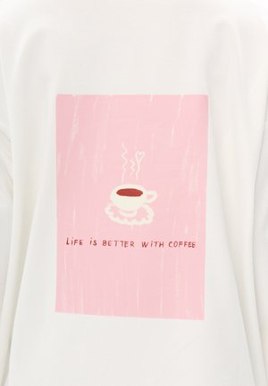 Sweat-shirt blanc avec un graphisme rectangulaire rose. Il représente une tasse de café fumante sur une soucoupe blanche avec le texte "La vie est meilleure avec du café."