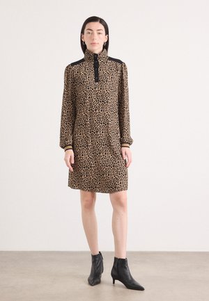 Leopard print dress with a high collar, long sleeves, and button detailing. Black accents on shoulders, paired with black ankle boots.