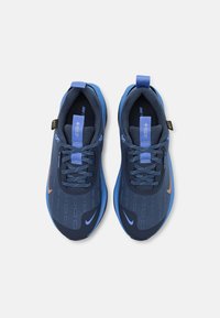 Niebieskie buty sportowe z fakturowaną cholewką, kontrastującymi jaśniejszymi akcentami w odcieniu niebieskiego oraz odblaskowymi detalami. Posiadają sznurówki oraz pętelkę do łatwego zakładania.