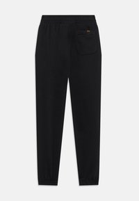 Black jogger pants made of soft fabric, featuring an elastic waistband, cuffed ankles, and a single back pocket with a logo accent.