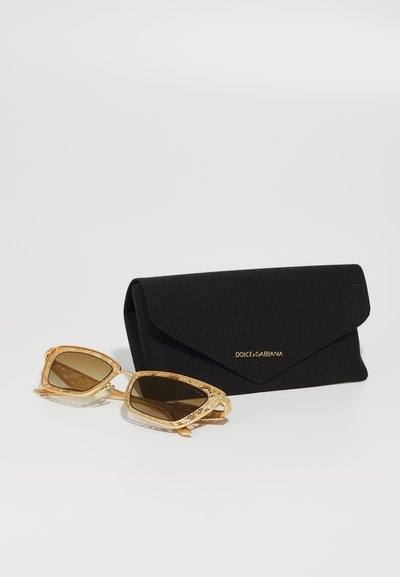 Slnečné okuliare Dolce & Gabbana so zlatým kovovým rámom, zložitým detailom a hnedými šošovkami, spolu s čiernym textilným puzdrom s logom.