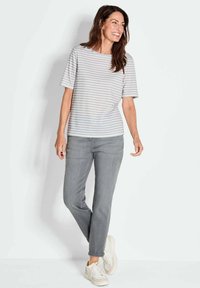 Grijs en wit gestreepte T-shirt met korte mouwen, gecombineerd met grijze jeans en witte sneakers. Gladde stof en een relaxte pasvorm.