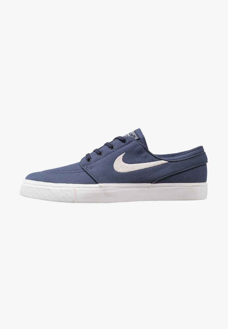 Sneaker basso blu navy con suola bianca e logo Nike swoosh bianco, dotato di chiusura con lacci e upper in tessuto texturizzato.