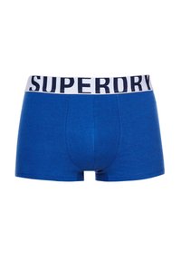 Blauwe boxershorts met een aansluitend ontwerp, gemaakt van zachte stof. Heeft een witte tailleband met "SUPERDRY" in marineblauw bedrukt.
