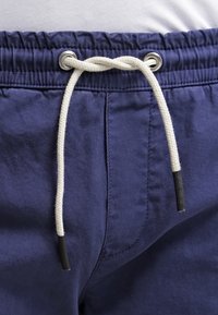 Marineblauwe shorts met een tailleband met trekkoord van witte touw en zwarte kunststof punten, gemaakt van een gladde stof met subtiele stiksels.