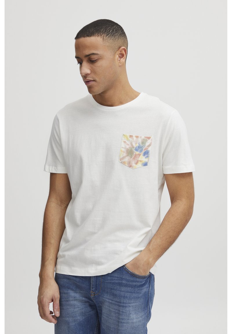 Hvid bomulds t-shirt med en lille lomme, der har et multicolor abstrakt mønster. Korte ærmer, rund halsudskæring, afslappet pasform.