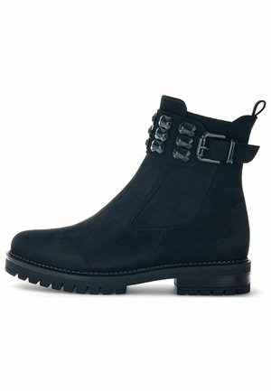Stivale alla caviglia in suede nero con una tracolla texturizzata decorata da borchie nere, punta tonda e suola spessa.