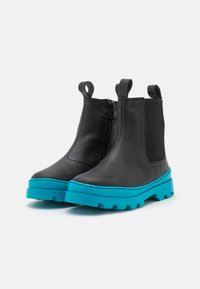 Bottines en cuir noir avec un panneau latéral élastique noir texturé et une semelle épaisse turquoise vibrante. Comprend des languettes pour un enfilage facile.