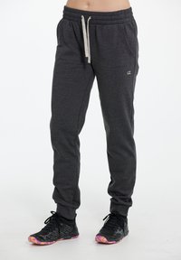 Grå sweatpants tillverkade av ett mjukt material med resårmidja, dragsko, sidofickor och en liten logotyp på låret.