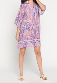 Violet paisley-kuvioinen mekko, jossa on kauluksellinen pääntie ja kolme neljännespituista kellohametta, esittäen virtaavaa siluettia ja kevyttä kangasta.