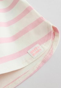 Tissu doux à rayures horizontales roses et blanches, avec une petite étiquette cousue portant l'inscription "HOPPY BUNNY" en texte rose clair.