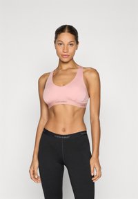 Ljusrosa sport-bh med bågformad halsringning och breda axelband; svarta leggings med en elastisk midjeband med varumärke. Slät tyg, kroppsnära design.