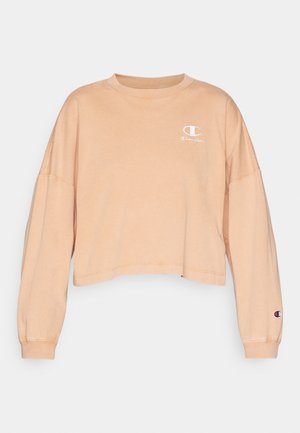 Sweatshirt court à manches longues en tissu pêche clair. Présente un petit logo blanc sur la poitrine et un écusson logo sur la manche.