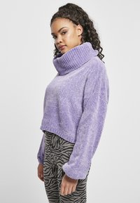 Pull-over court en tissu texturé violet avec un large col roulé côtelé et des manches ballons, associé à un legging gris à rayures zèbre.