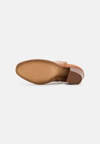 Suola di scarpa in pelle marrone con grip in gomma texturizzato, tacco curvo e finitura complessiva liscia. Presenta un leggero angolo sulla punta.