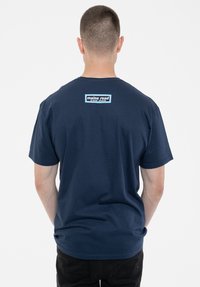 Navy blue cotton t-shirt with short sleeves, featuring a rectangular logo in white and blue at the upper back. Classic crew neckline.
